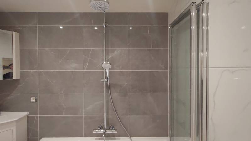 Pose méticuleuse du carrelage mural effet marbre, apportant élégance et modernité à la salle de bain de Taverny (95)